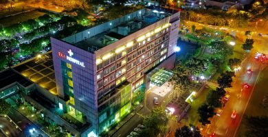 hospital beside vehicle park and road at night