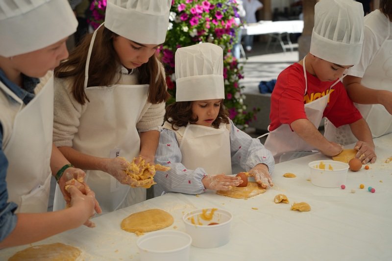 Niños disfrutan del taller «Haz tu propio hornazo» en la plaza de España